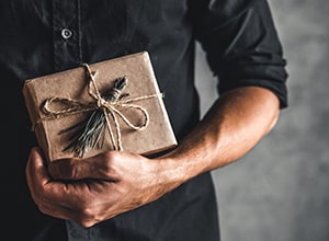 Man holding neutral wrapped present.