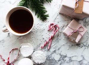 Mug of coffee next to candy canes and holiday gifts.