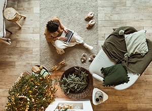 Woman sitting next to Christmas tree while working from home.