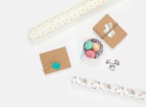 Rolls of wrapping paper, gift boxes and tin of macarons.