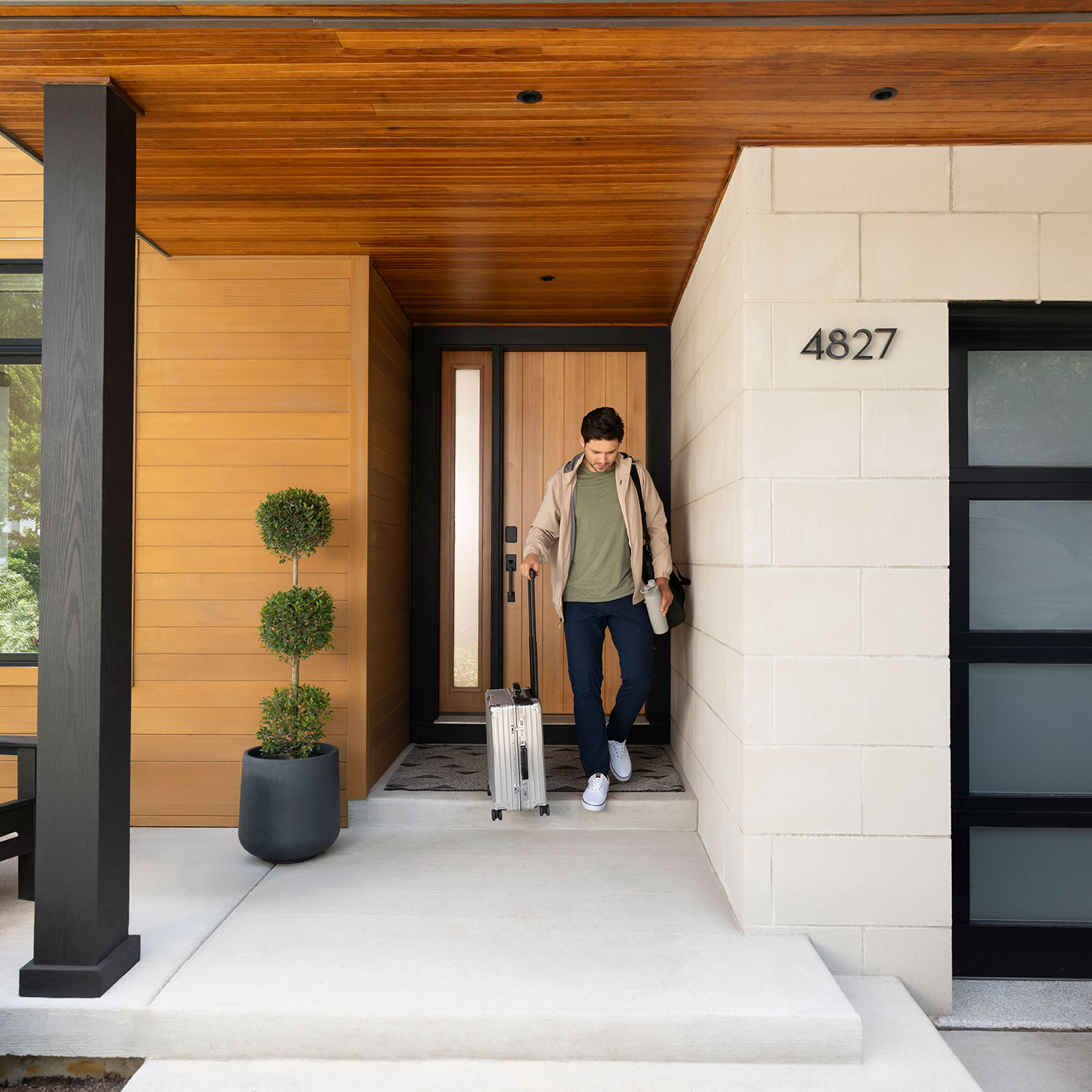 Man with suitcase leaves his home safe with a Schlage Sense Pro UWB smart lock for premium security