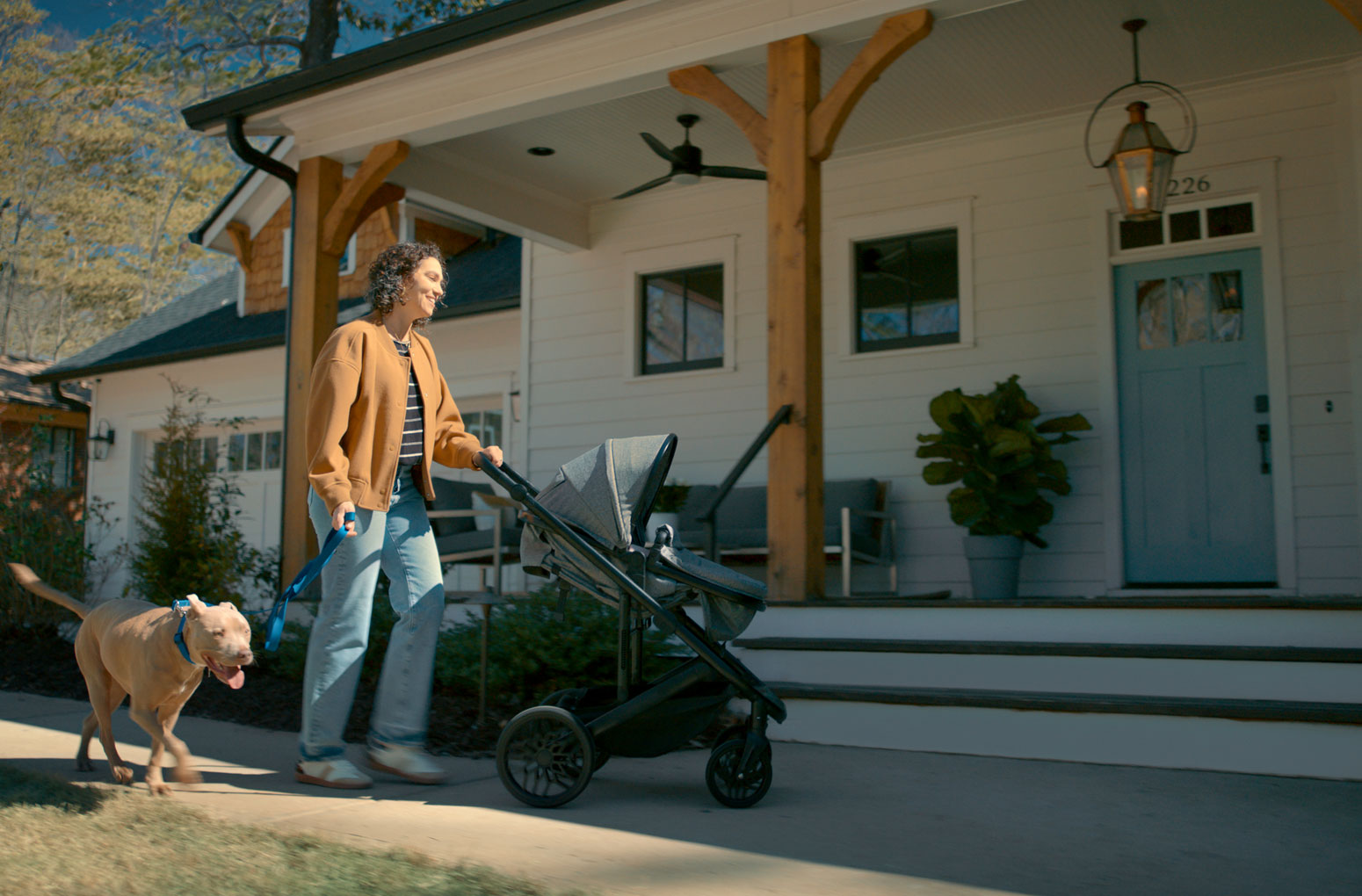 Woman managing a stroller and a dog uses the Schlage Sense Pro UWB smart lock for hands-free unlocking