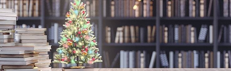 Lit Christmas tree in library of books.