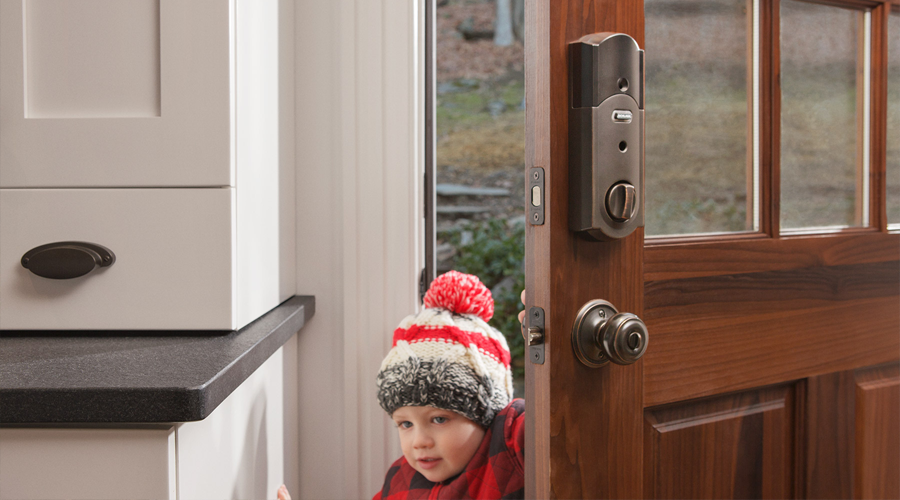 Little boy entering his home wearing a winter hat.