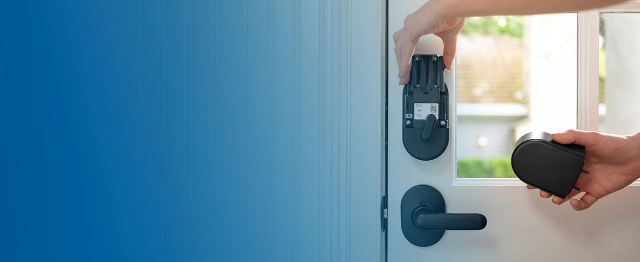 Person removing battery pack from Schlage Arrive Smart Lock while holding battery cover in opposite hand