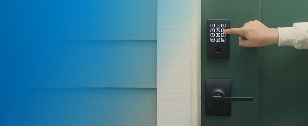 Person's hand entering access code on lit keypad of matte black Schlage Arrive Smart Lock