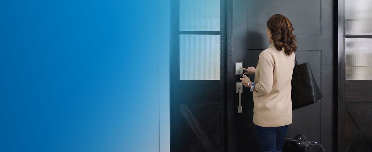 Woman with purse and cell phone in hand entering a access code on touchscreen of Schlage Encode Plus Smart Lock