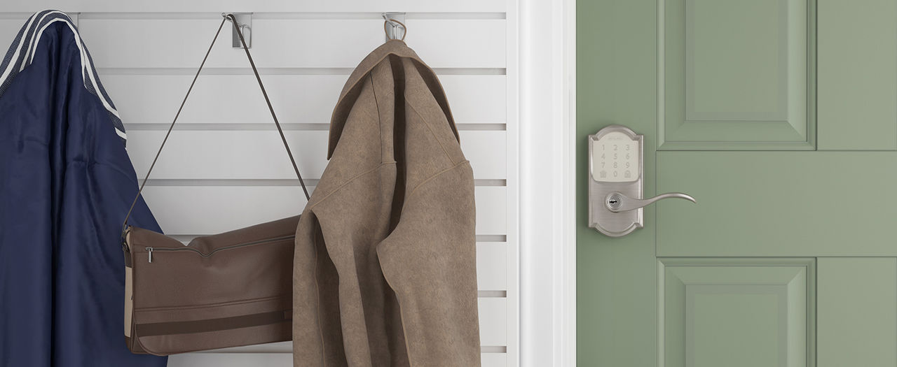 Satin Nickel Schlage Encode Smart Lever installed on closed door in garage mudroom next to hanging coats and bags